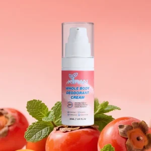 XiRAN Whole Body Deodorant Cream bottle surrounded by persimmons and mint leaves against a peach-colored background.